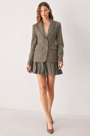 A woman modeling a matching two-piece blazer and pleated mini skirt set in a brown and beige houndstooth pattern | FREEMARKET