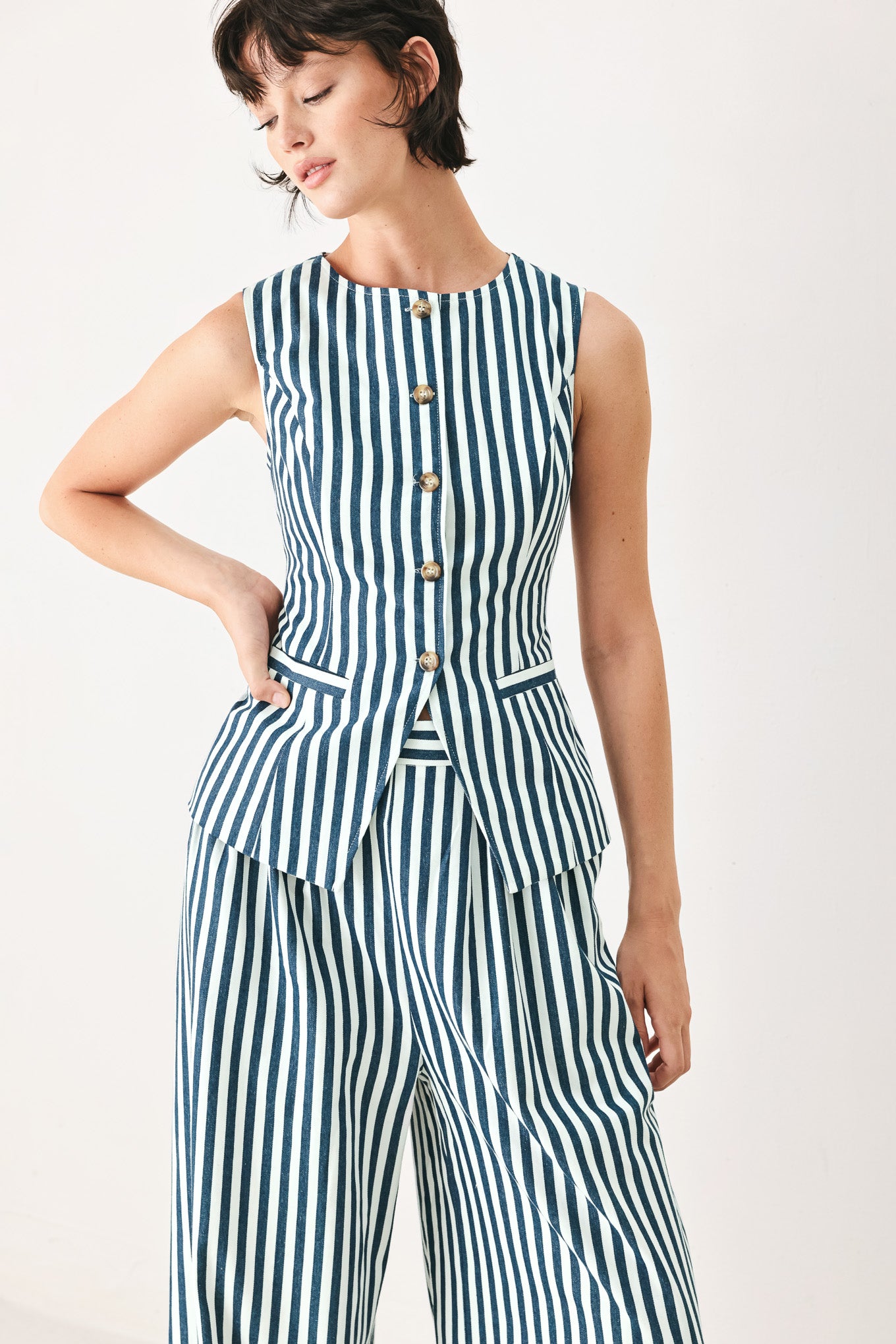 Woman wearing a blue and white striped sleeveless vest with buttons | FREEMARKET
