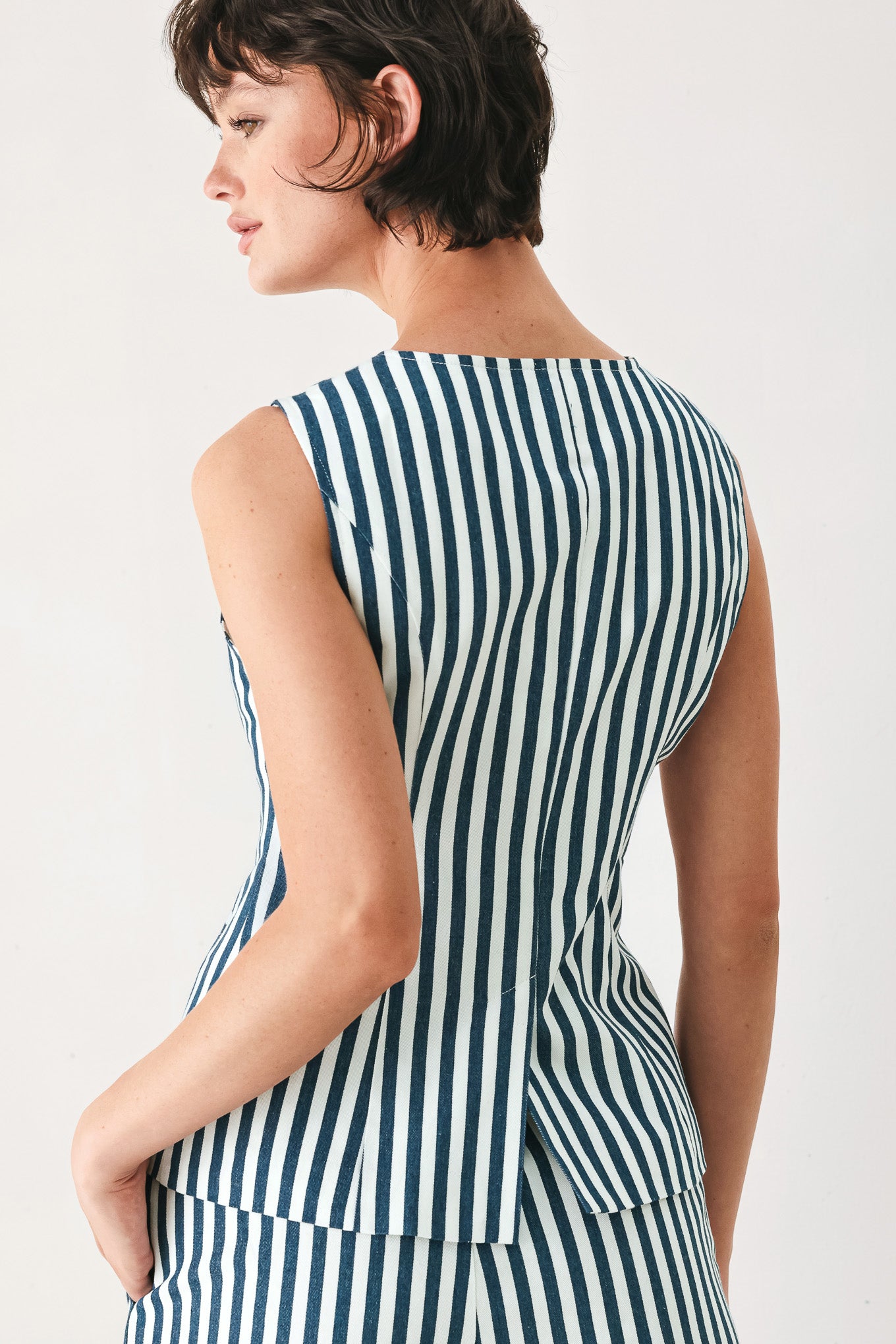Woman wearing a blue and white striped sleeveless vest with buttons | FREEMARKET