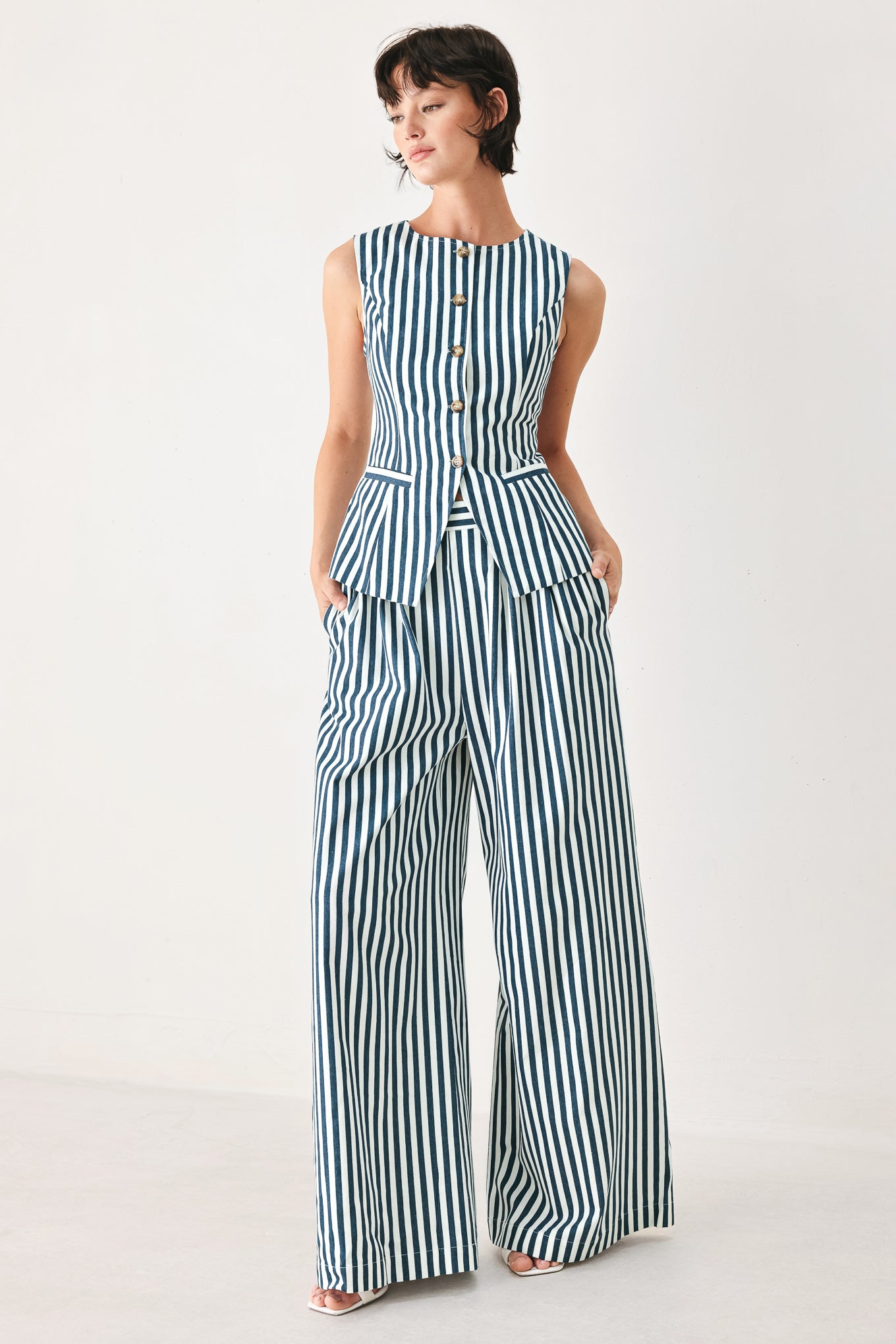 Woman wearing a blue and white striped sleeveless vest with buttons | FREEMARKET