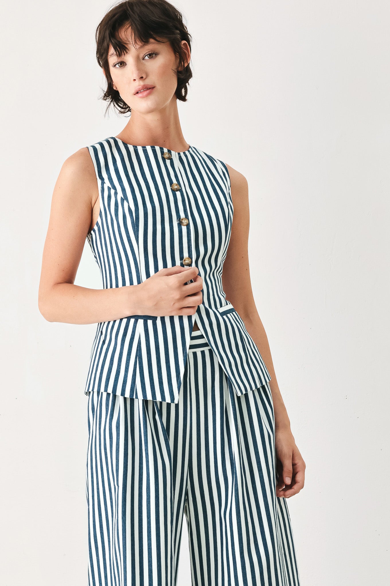 Woman wearing a blue and white striped sleeveless vest with buttons | FREEMARKET