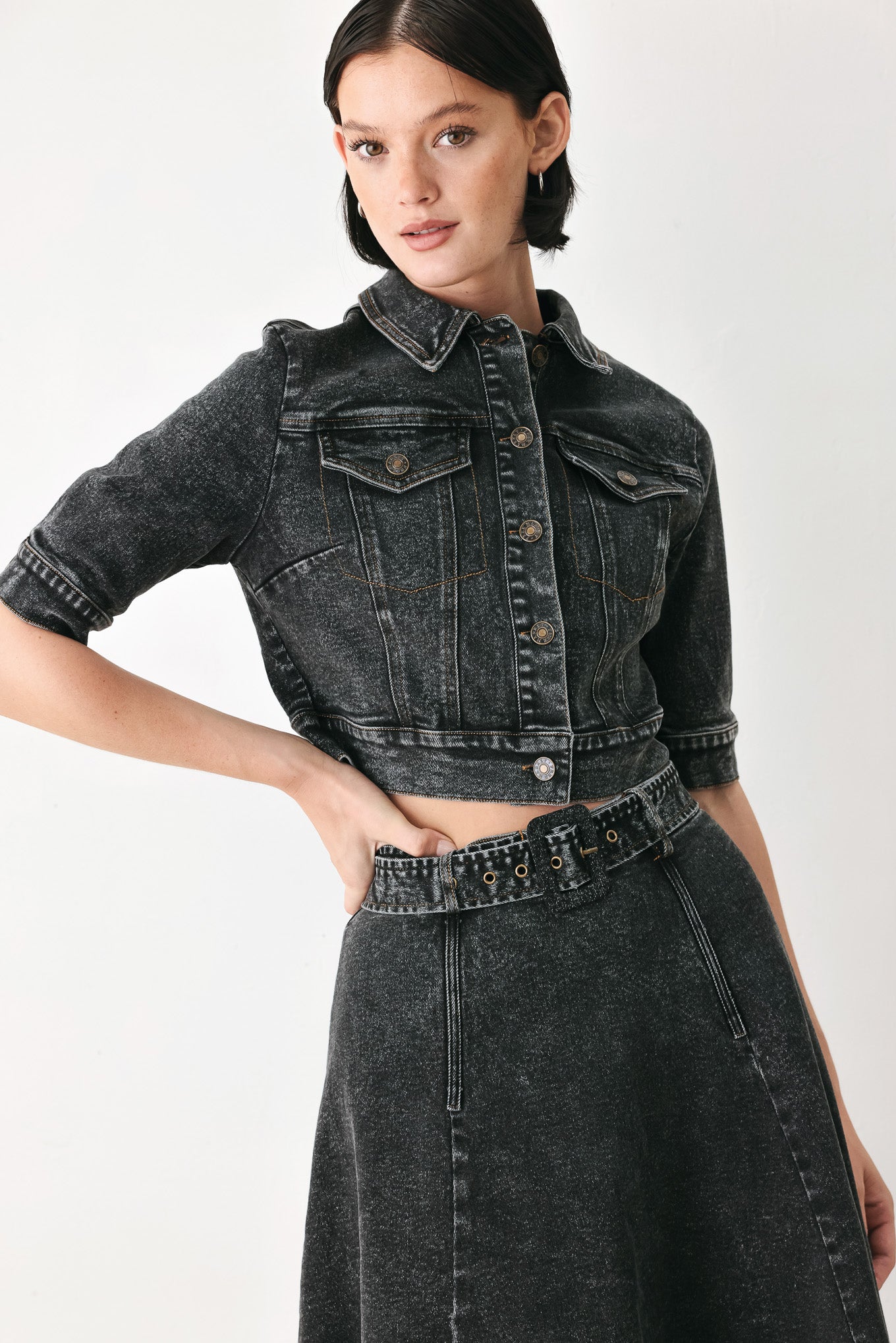 A model wearing a cropped, short-sleeved black acid-wash denim jacket with a band collar and button front | FREEMARKET