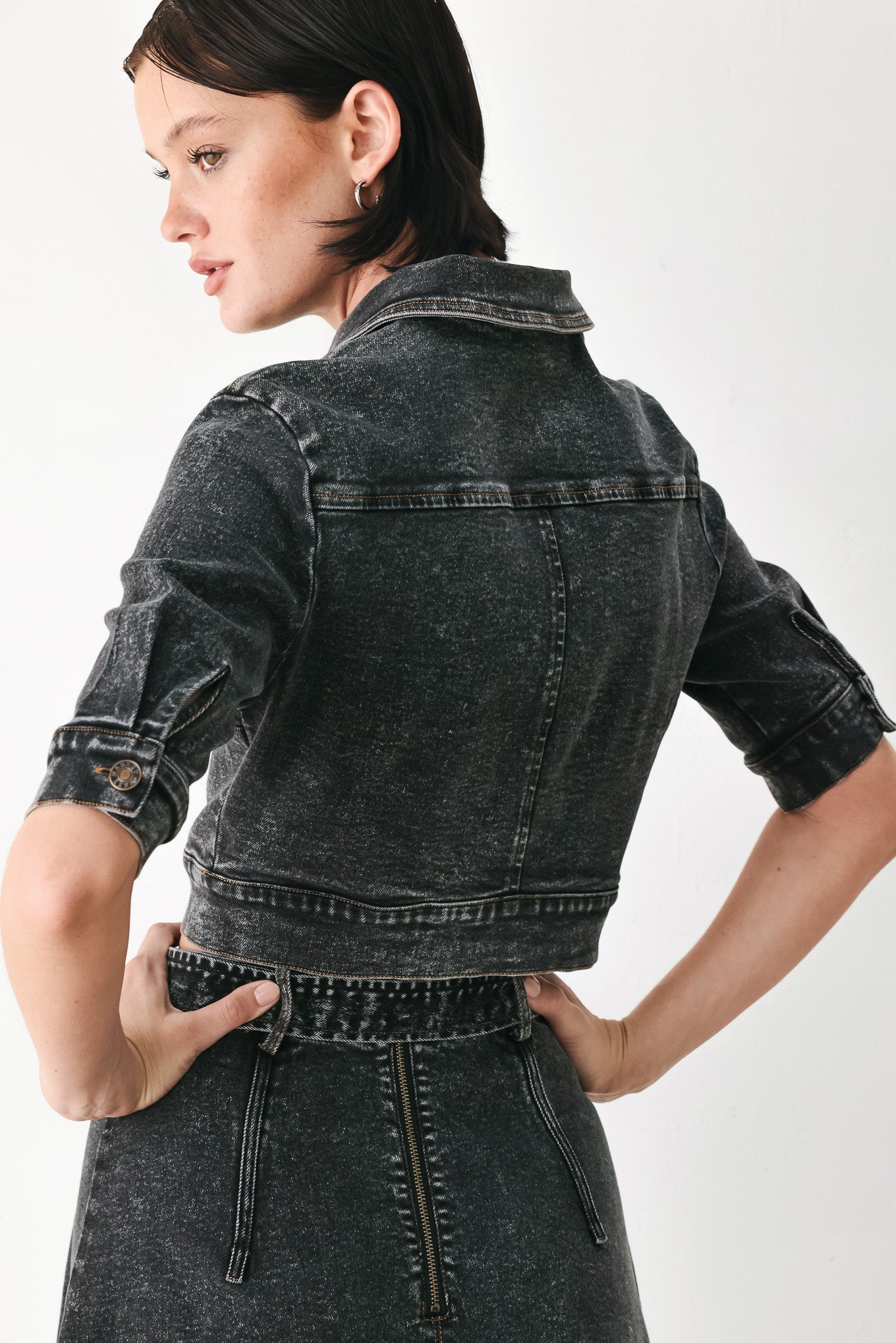 A model wearing a cropped, short-sleeved black acid-wash denim jacket with a band collar and button front | FREEMARKET