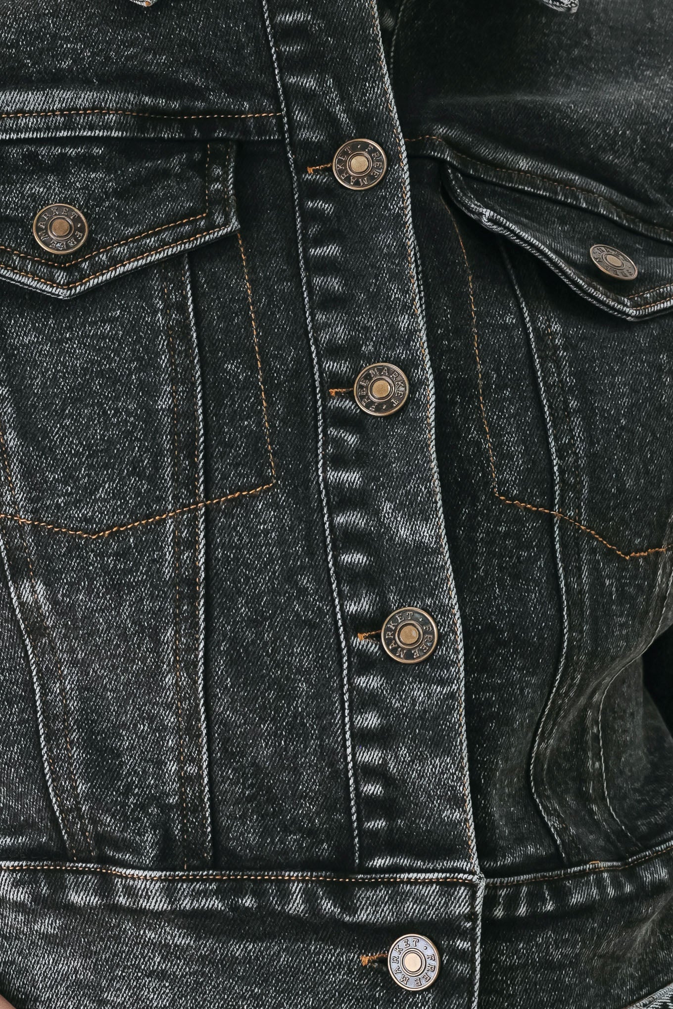 A model wearing a cropped, short-sleeved black acid-wash denim jacket with a band collar and button front | FREEMARKET