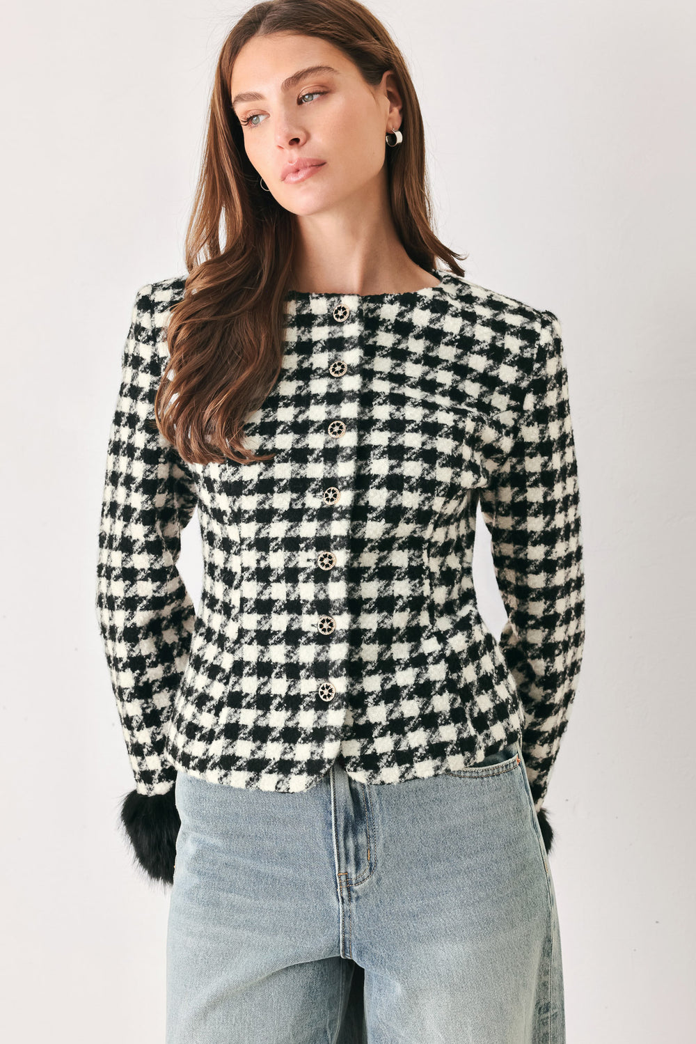 Woman wearing a black and white long sleeve houndstooth tailored jacket with front button closure and faux fur trim around the wrists | FREEMARKET