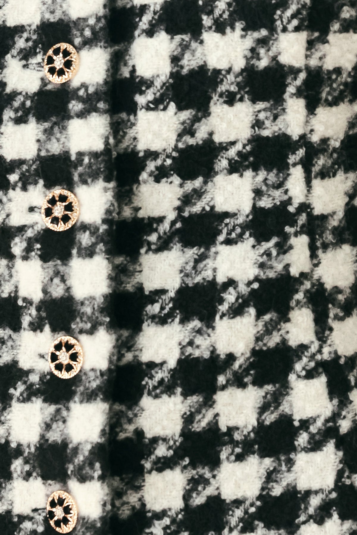 Woman wearing a black and white long sleeve houndstooth tailored jacket with front button closure and faux fur trim around the wrists | FREEMARKET