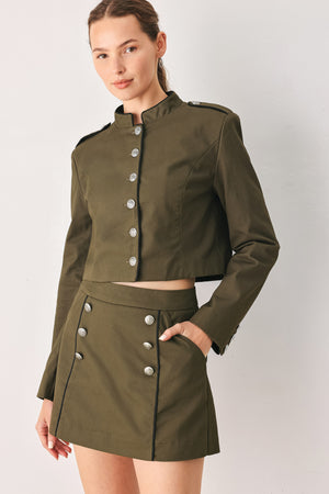 A close-up of a model wearing an olive green cropped jacket with a high stand collar, silver buttons down the front, and shoulder epaulets | FREEMARKET