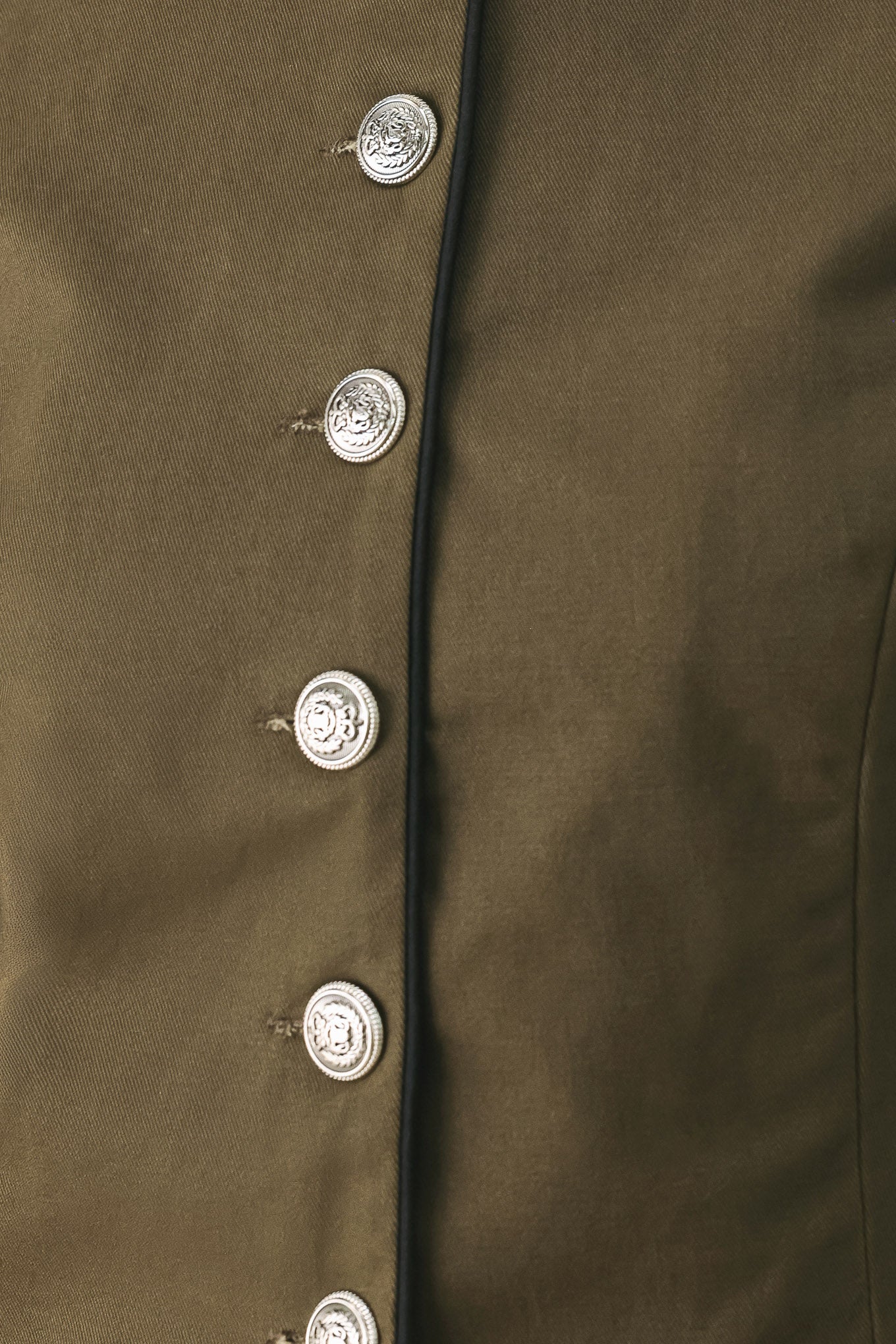 A close-up of a model wearing an olive green cropped jacket with a high stand collar, silver buttons down the front, and shoulder epaulets | FREEMARKET
