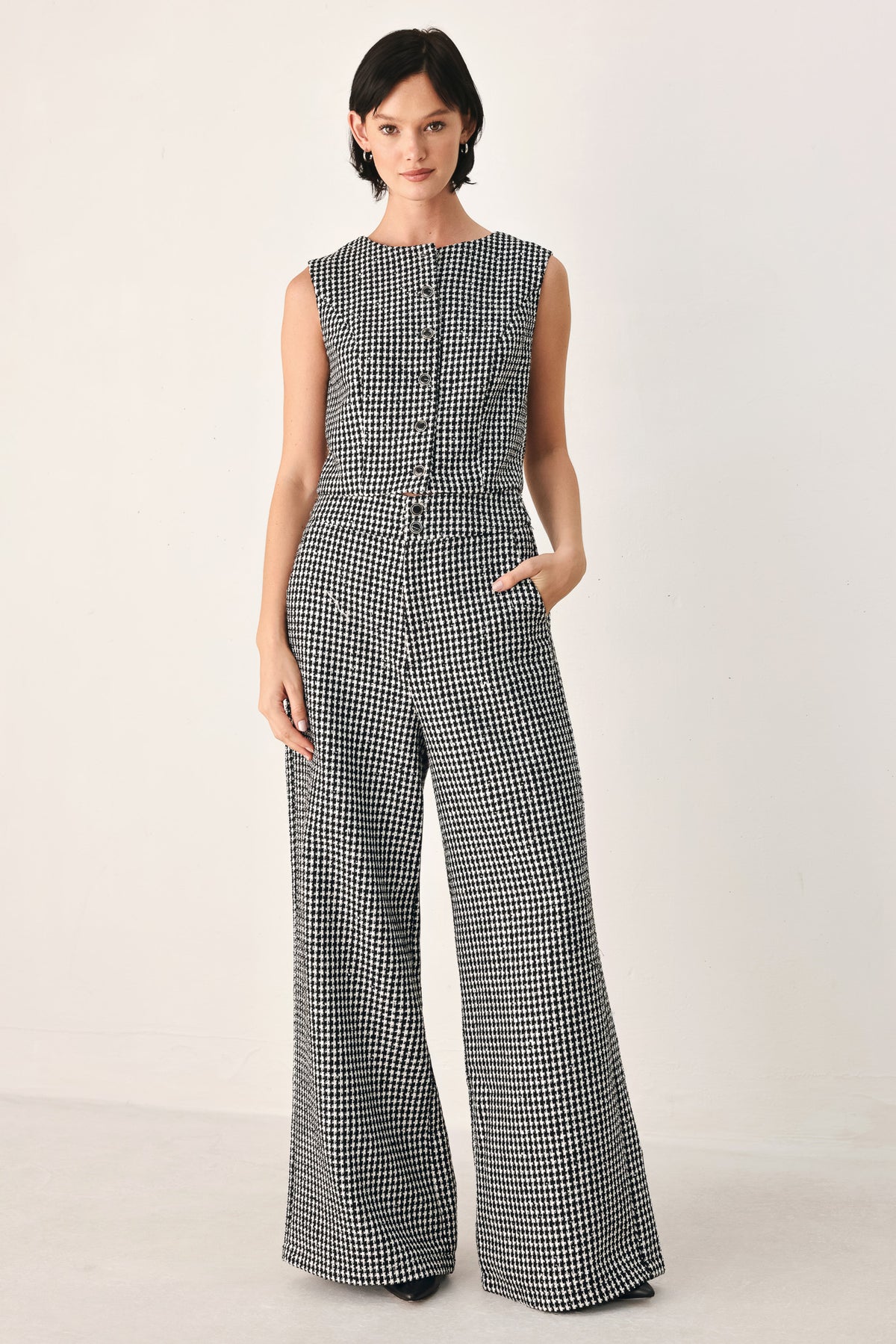 A woman modeling a sleeveless black and white houndstooth cropped vest with a button-front bodice | FREEMARKET