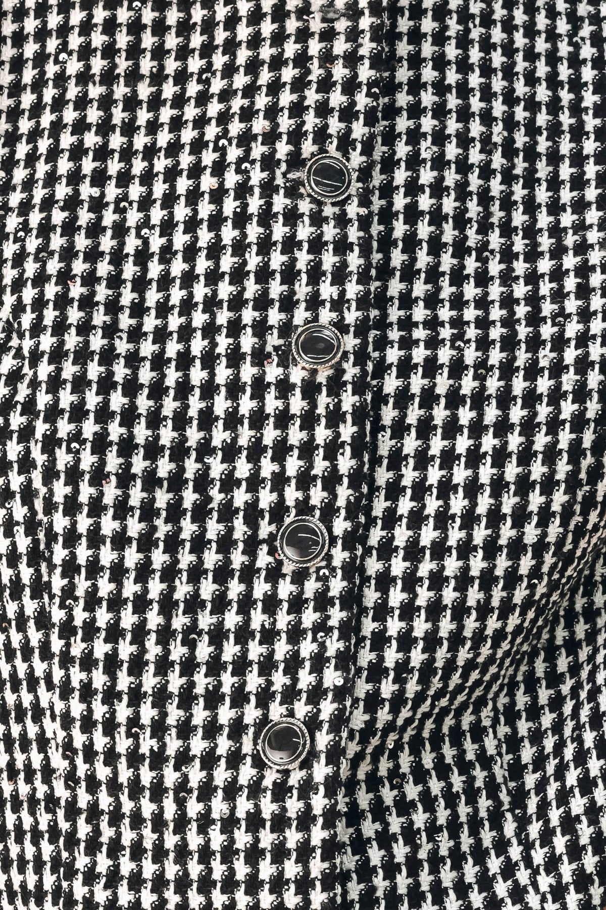 A woman modeling a sleeveless black and white houndstooth cropped vest with a button-front bodice | FREEMARKET
