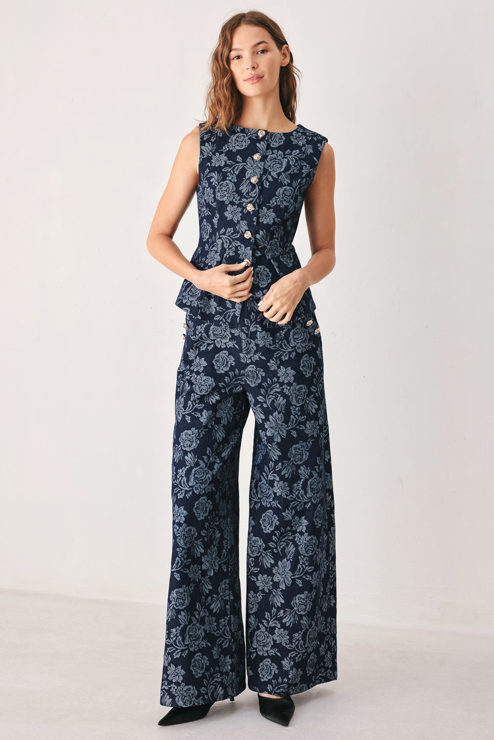 A woman wearing a sleeveless navy blue denim jacquard vest with a light blue floral pattern and gold-tone buttons down the front | FREEMARKET