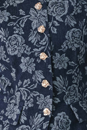 A woman wearing a sleeveless navy blue denim jacquard vest with a light blue floral pattern and gold-tone buttons down the front | FREEMARKET