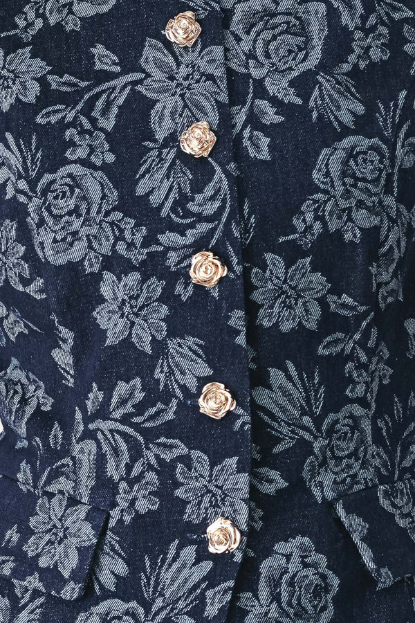 A woman wearing a sleeveless navy blue denim jacquard vest with a light blue floral pattern and gold-tone buttons down the front | FREEMARKET