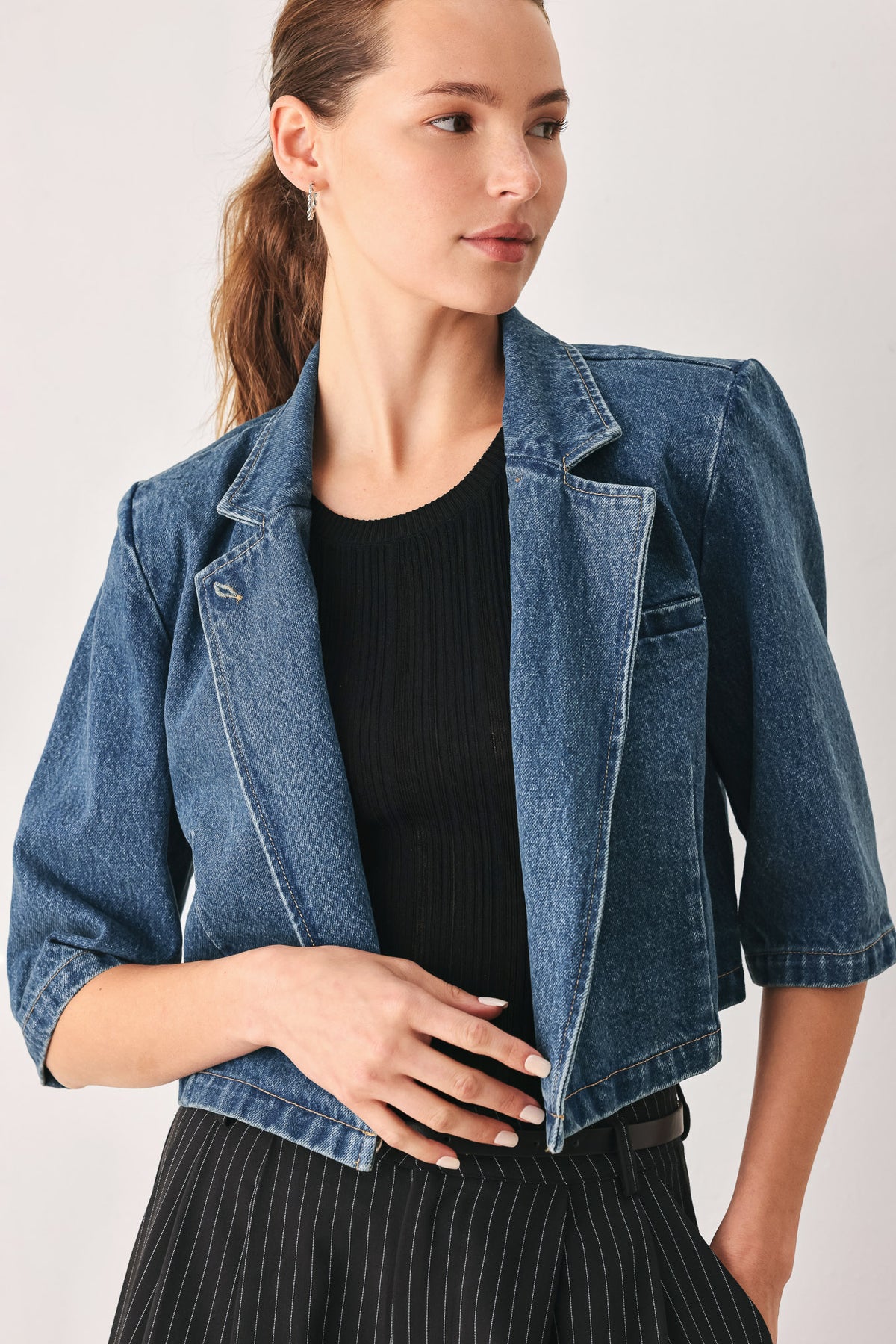 A woman wearing a cropped blue denim jacket with a high stand collar, structured shoulders, and elbow-length sleeves | FREEMARKET
