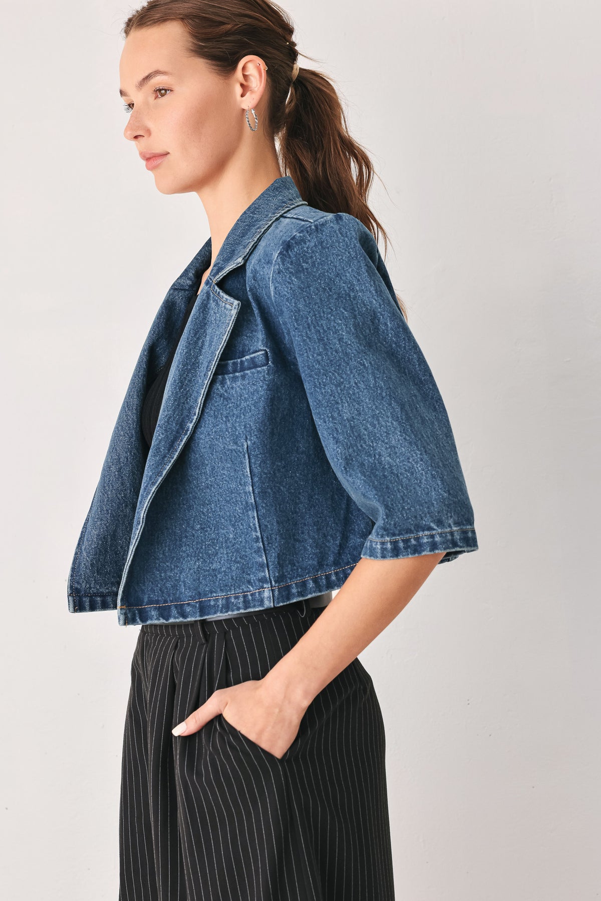 A woman wearing a cropped blue denim jacket with a high stand collar, structured shoulders, and elbow-length sleeves | FREEMARKET