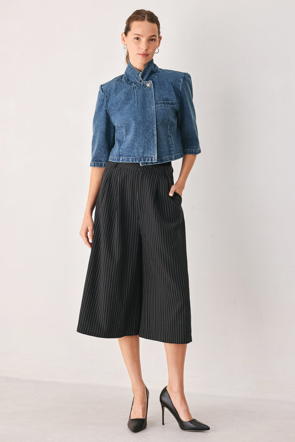 A woman wearing a cropped blue denim jacket with a high stand collar, structured shoulders, and elbow-length sleeves | FREEMARKET