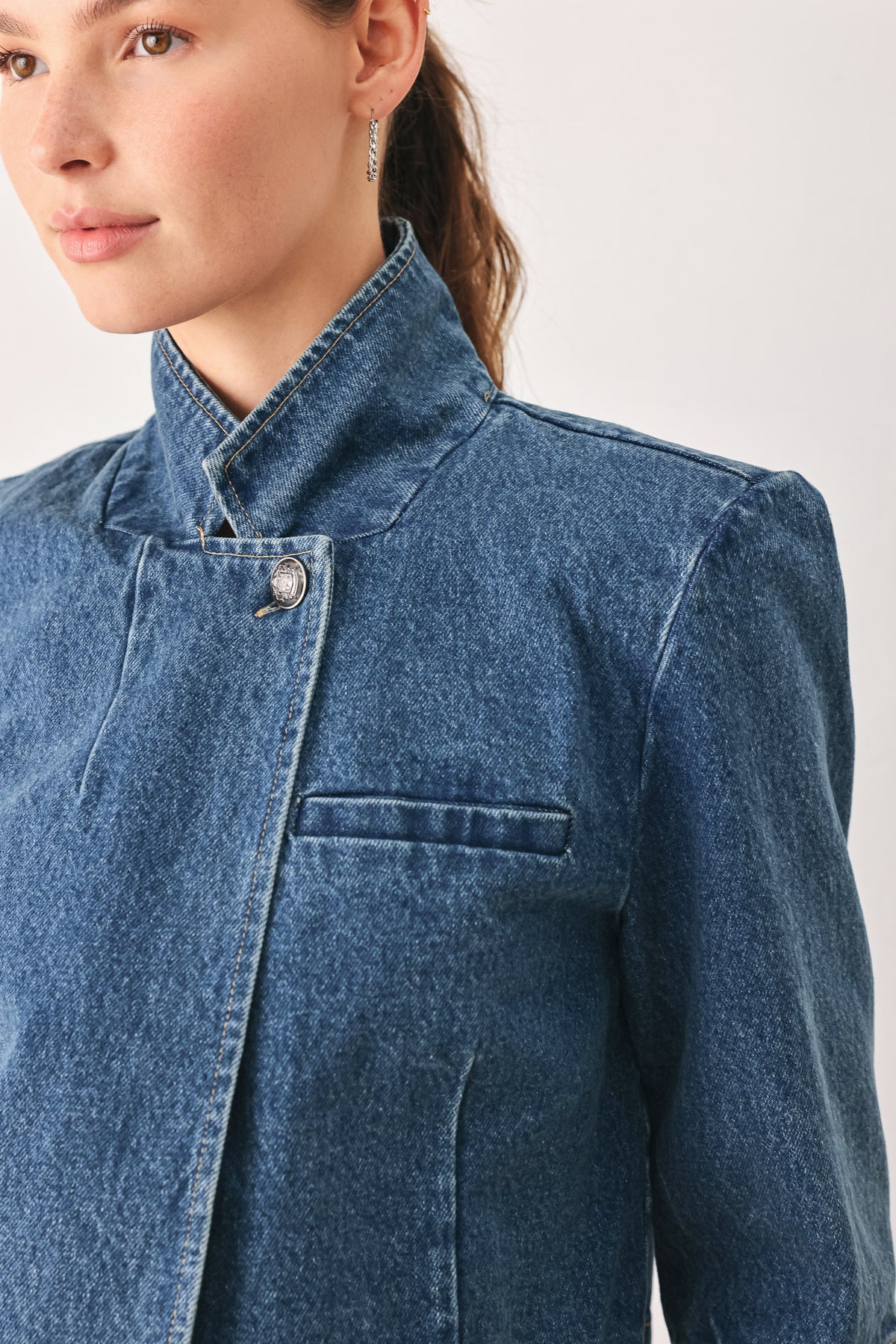 A woman wearing a cropped blue denim jacket with a high stand collar, structured shoulders, and elbow-length sleeves | FREEMARKET