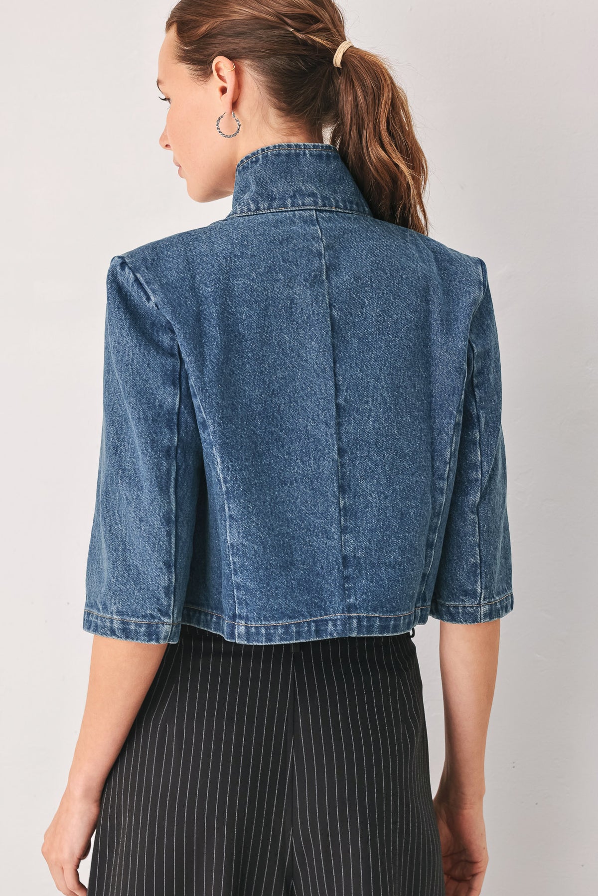 A woman wearing a cropped blue denim jacket with a high stand collar, structured shoulders, and elbow-length sleeves | FREEMARKET