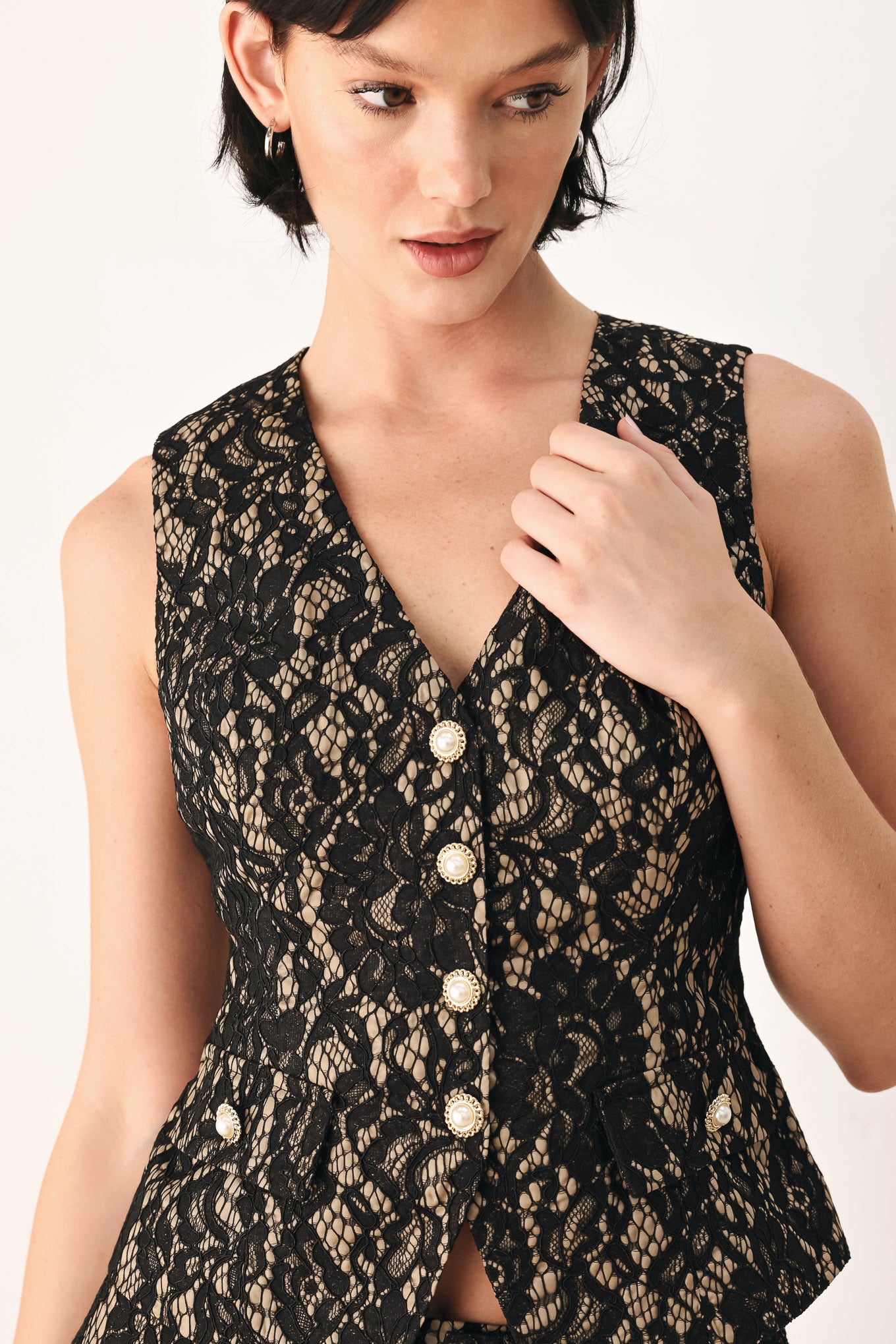 A woman wearing a sleeveless black lace vest with a V-neckline, front buttons | FREEMARKET