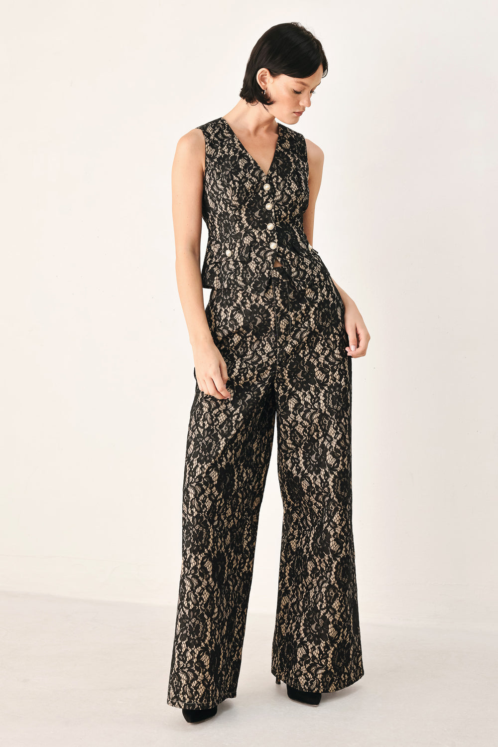 A woman wearing a sleeveless black lace vest with a V-neckline, front buttons | FREEMARKET