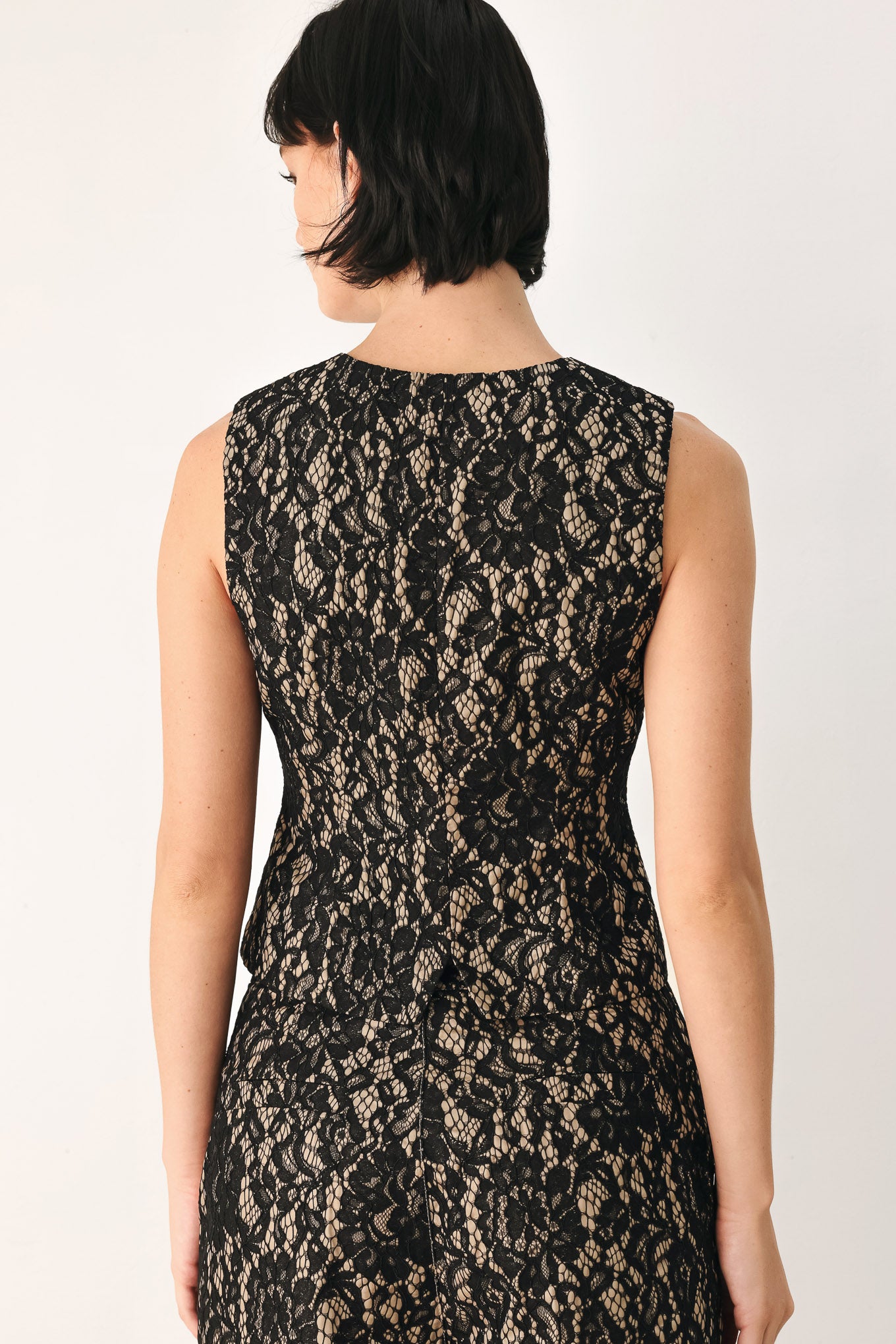 A woman wearing a sleeveless black lace vest with a V-neckline, front buttons | FREEMARKET