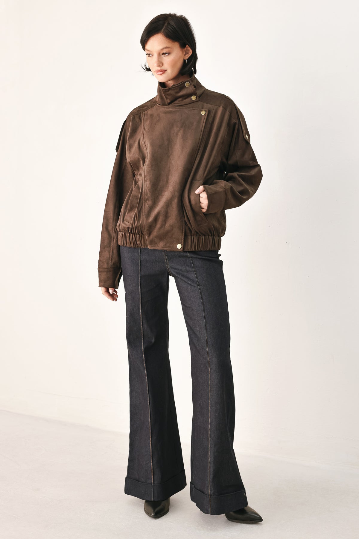 A woman wearing a dark brown suede jacket with a high collar and gold-tone snap buttons | FREEMARKET