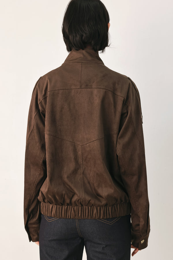 A woman wearing a dark brown suede jacket with a high collar and gold-tone snap buttons | FREEMARKET