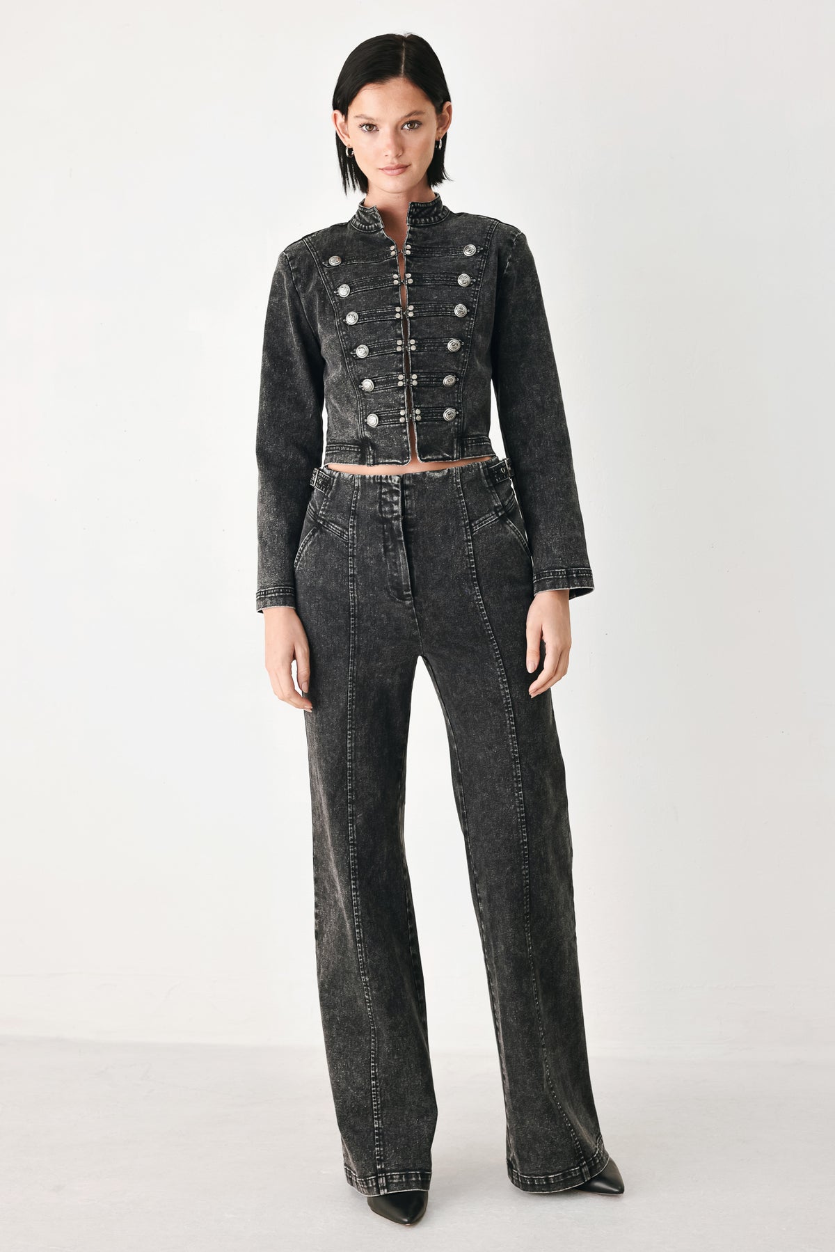 A model wearing a cropped black washed denim jacket with silver-tone decorative buttons | FREEMARKET