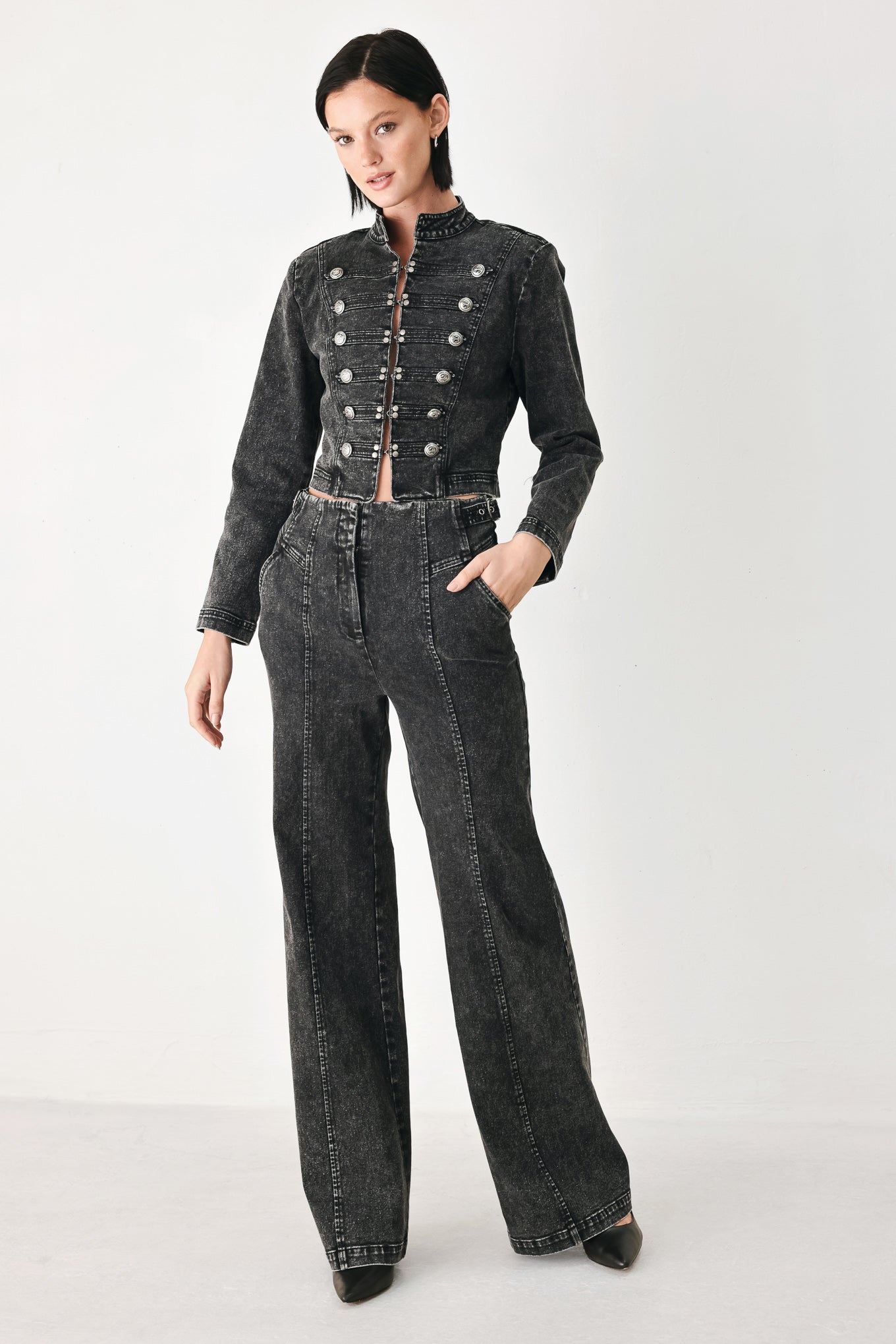 A model wearing a cropped black washed denim jacket with silver-tone decorative buttons | FREEMARKET