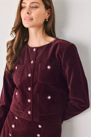 Woman wearing a burgundy long sleeve cropped jacket with buttons along the front center and on four front pockets | FREEMARKET