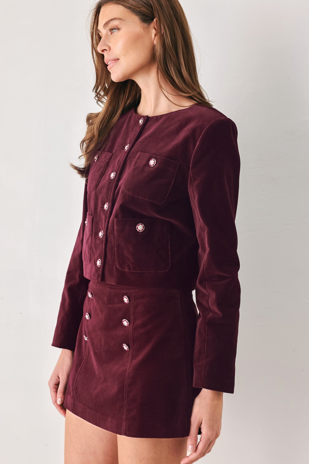 Woman wearing a burgundy long sleeve cropped jacket with buttons along the front center and on four front pockets | FREEMARKET