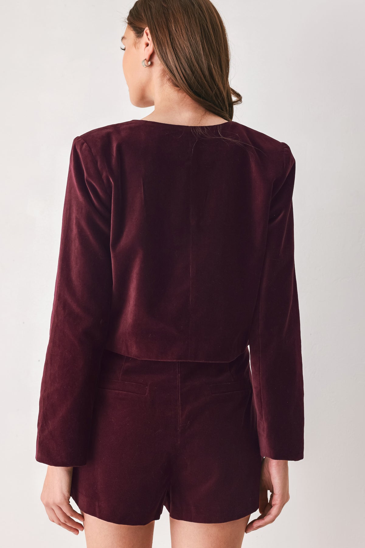 Woman wearing a burgundy long sleeve cropped jacket with buttons along the front center and on four front pockets | FREEMARKET
