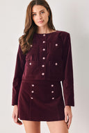 Woman wearing a burgundy long sleeve cropped jacket with buttons along the front center and on four front pockets | FREEMARKET