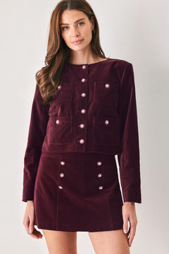 Woman wearing a burgundy long sleeve cropped jacket with buttons along the front center and on four front pockets | FREEMARKET
