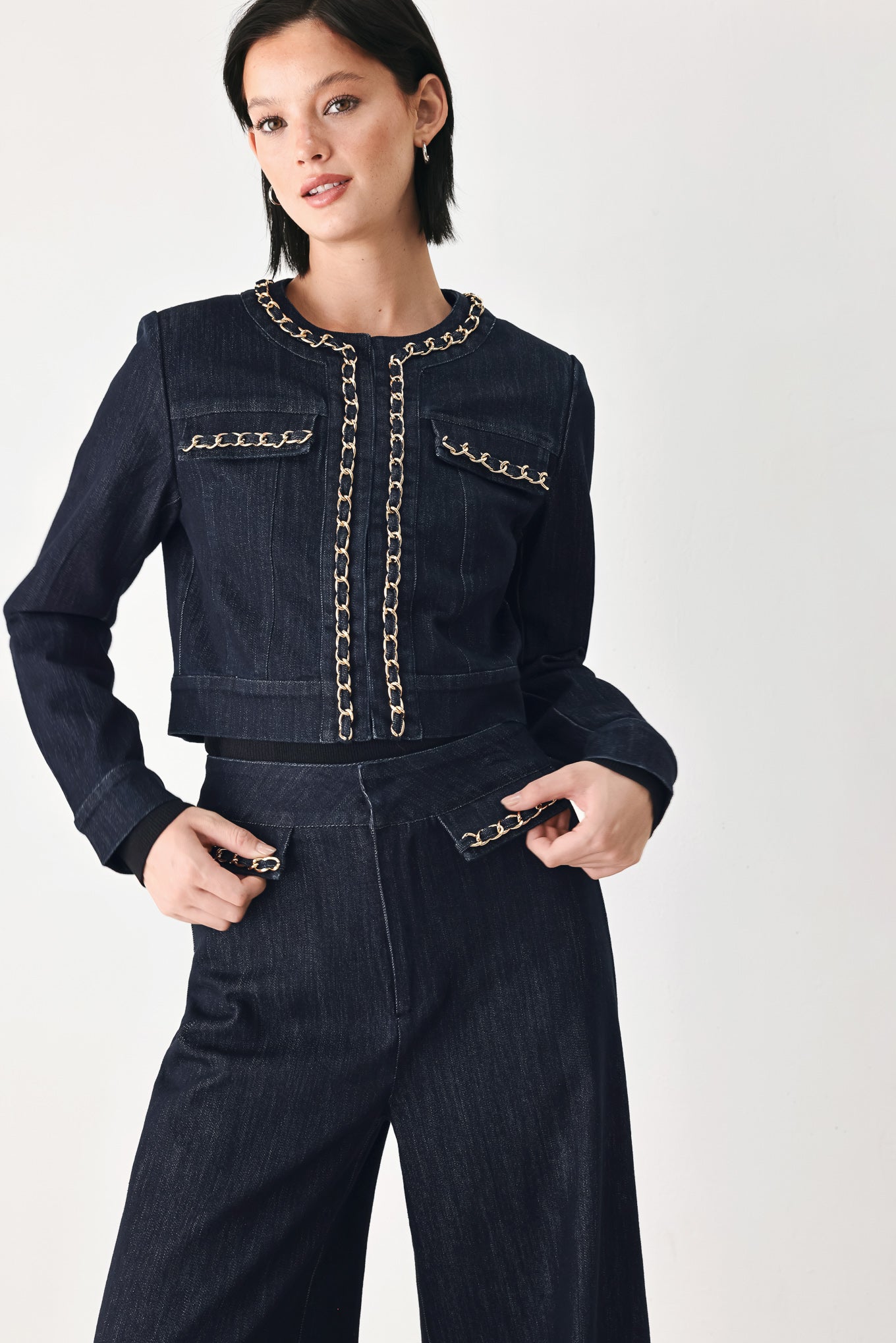 A model wearing a dark indigo denim jacket featuring gold chain trim details on the collar, chest pockets | FREEMARKET