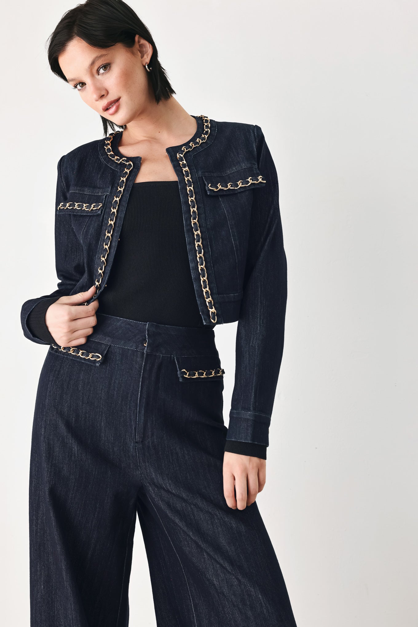 A model wearing a dark indigo denim jacket featuring gold chain trim details on the collar, chest pockets | FREEMARKET