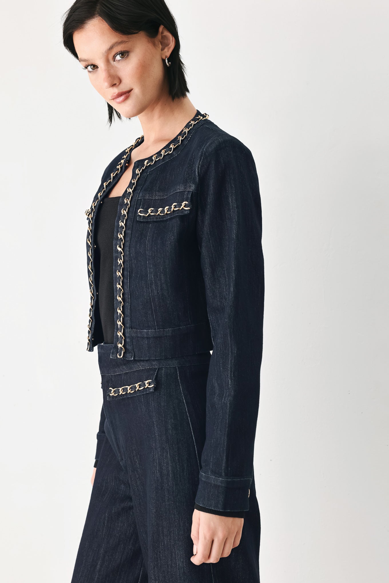 A model wearing a dark indigo denim jacket featuring gold chain trim details on the collar, chest pockets | FREEMARKET