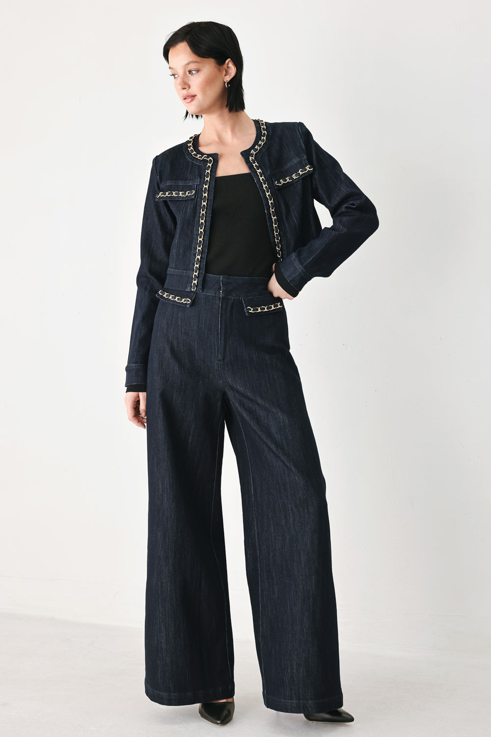 A model wearing a dark indigo denim jacket featuring gold chain trim details on the collar, chest pockets | FREEMARKET