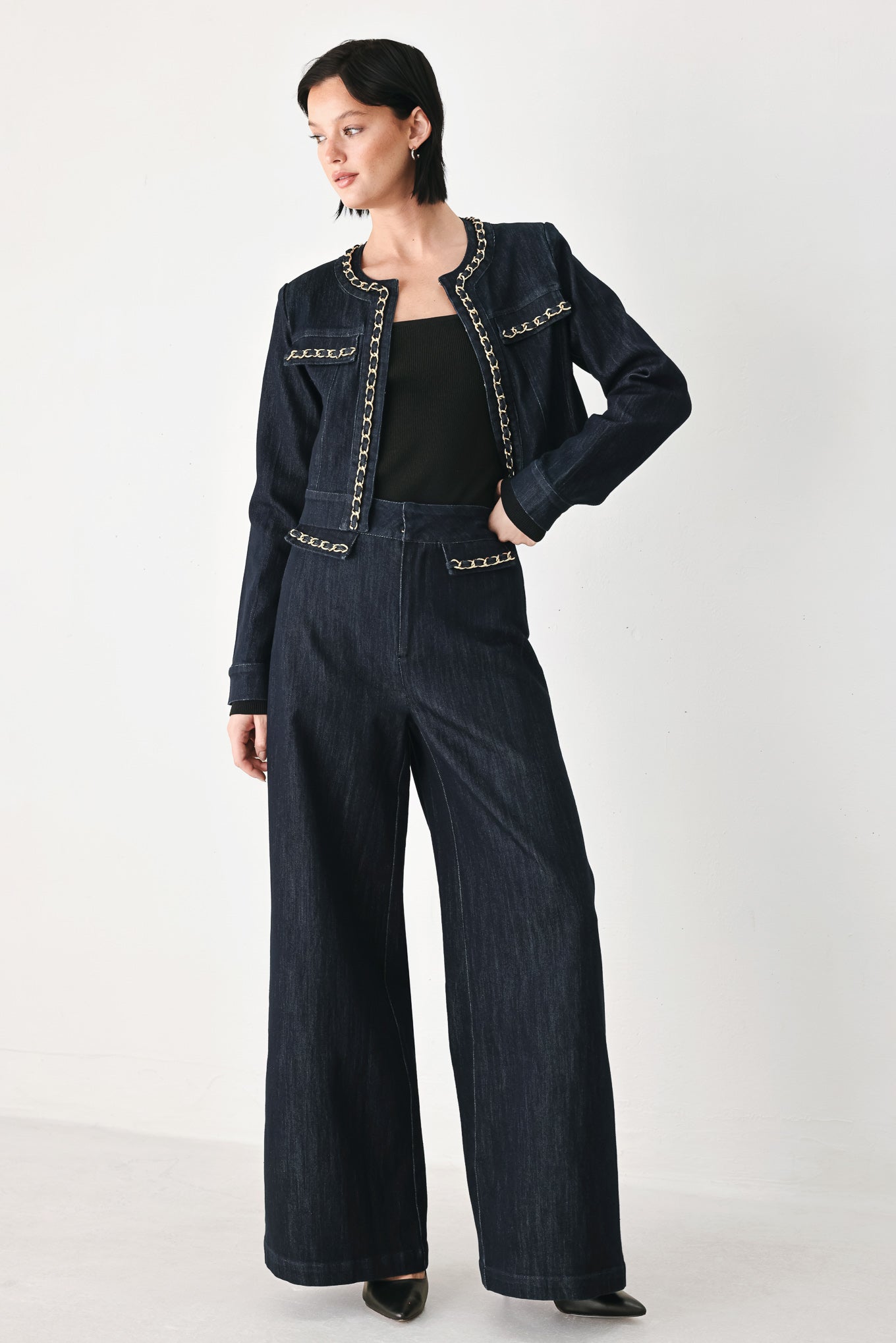 A model wearing a dark indigo denim jacket featuring gold chain trim details on the collar, chest pockets | FREEMARKET