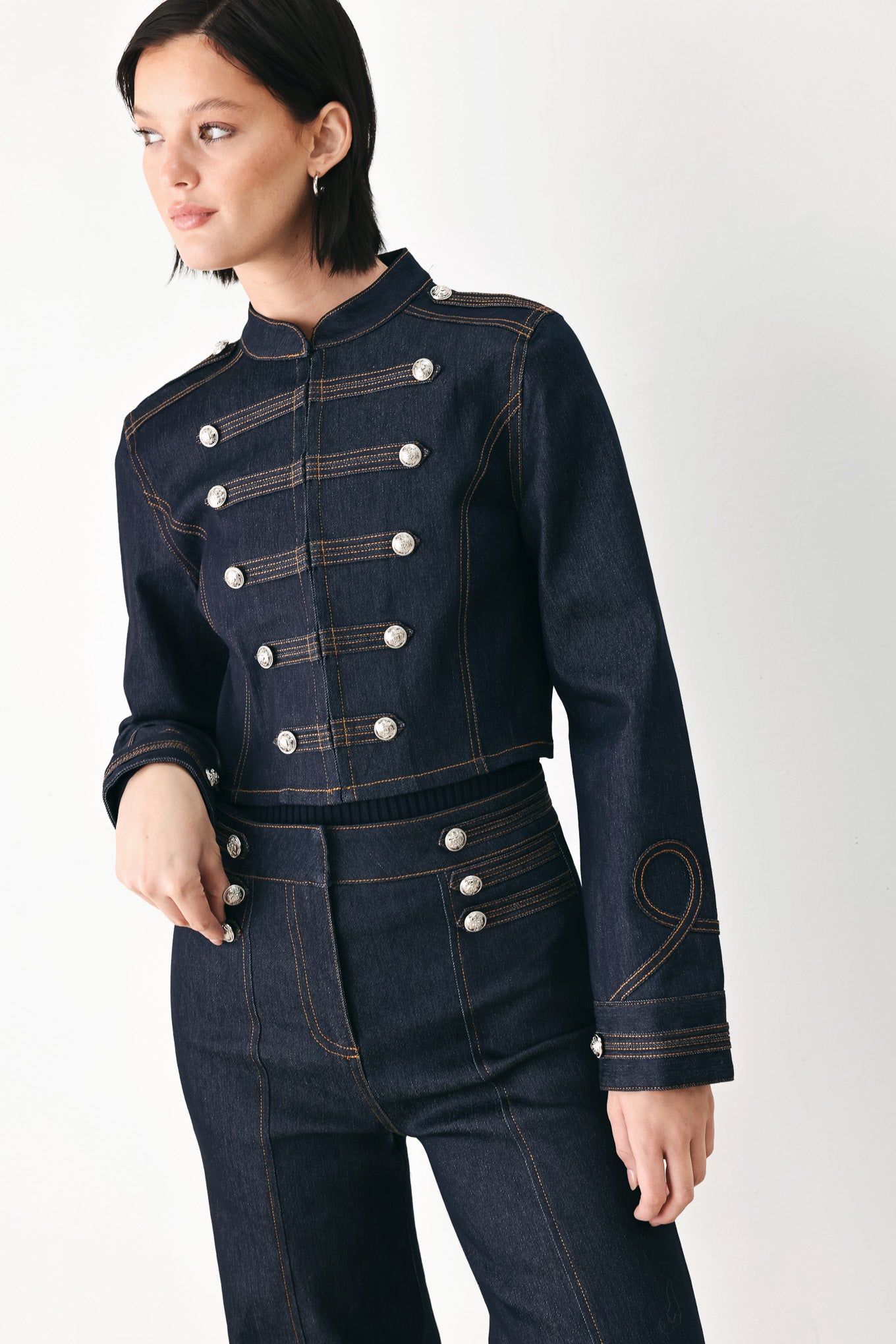 A model wearing a dark indigo denim military-style jacket with double-breasted silver buttons | FREEMARKET