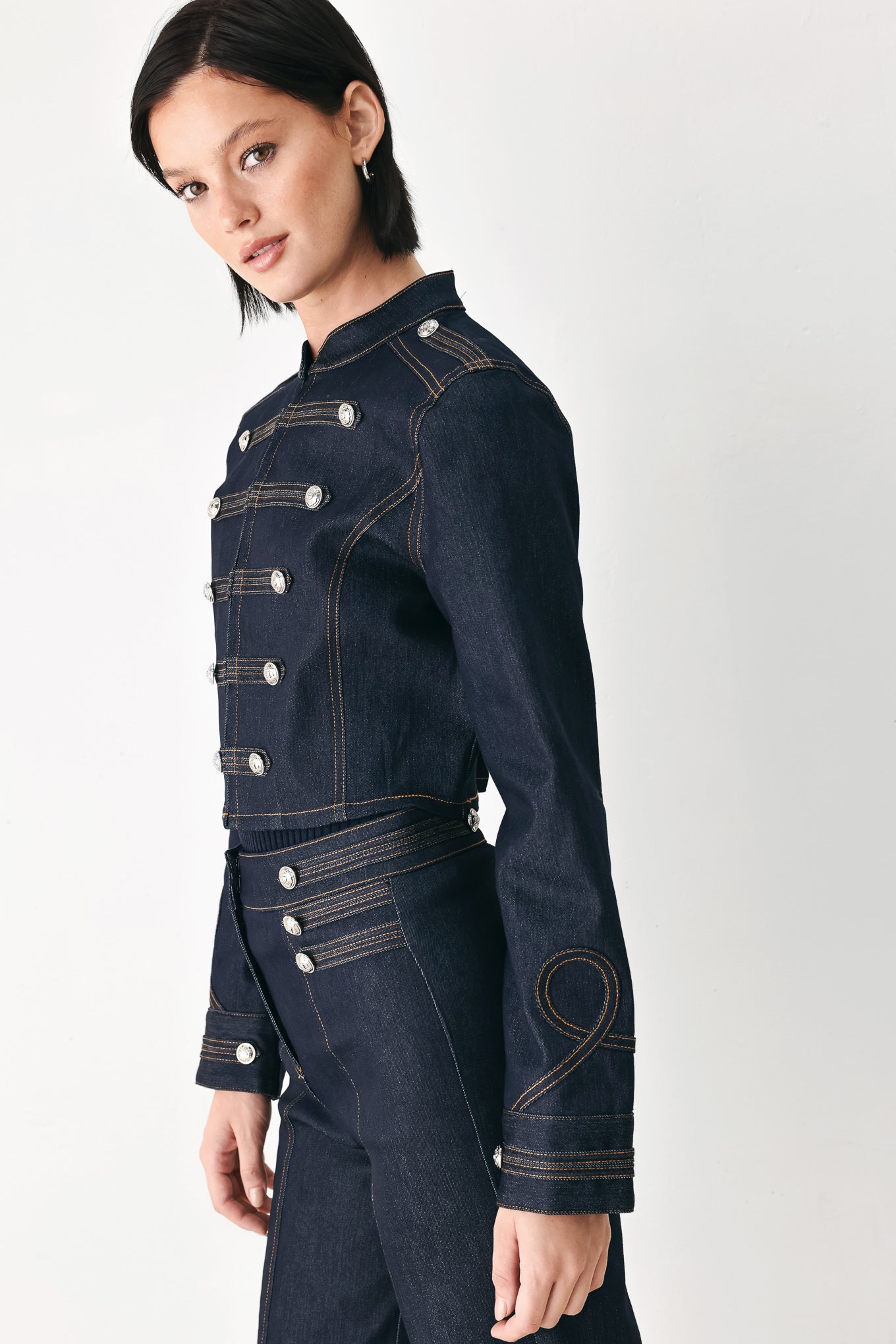 A model wearing a dark indigo denim military-style jacket with double-breasted silver buttons | FREEMARKET