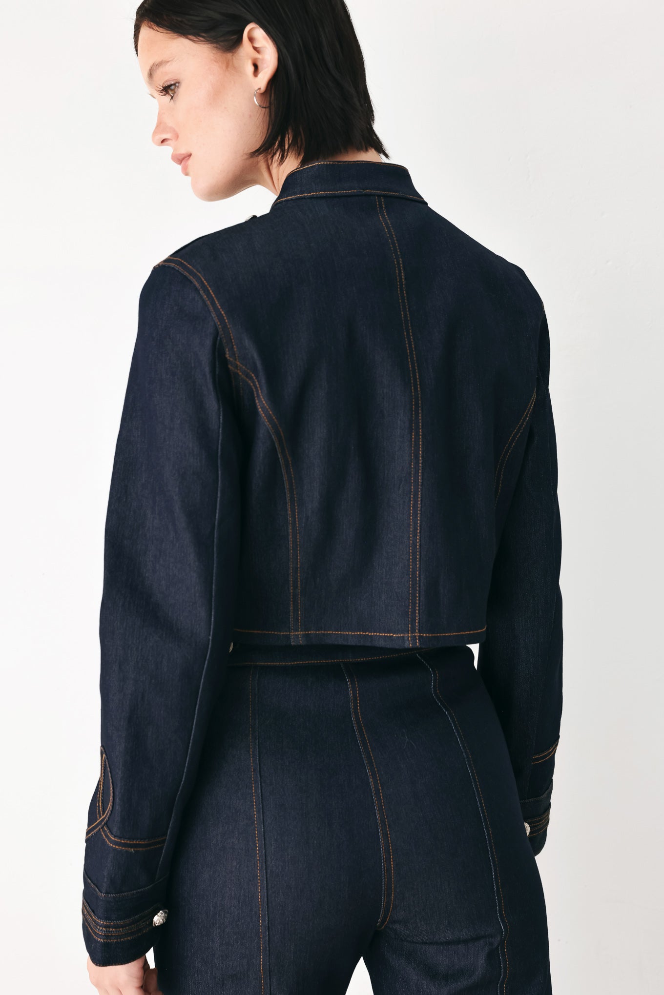 A model wearing a dark indigo denim military-style jacket with double-breasted silver buttons | FREEMARKET