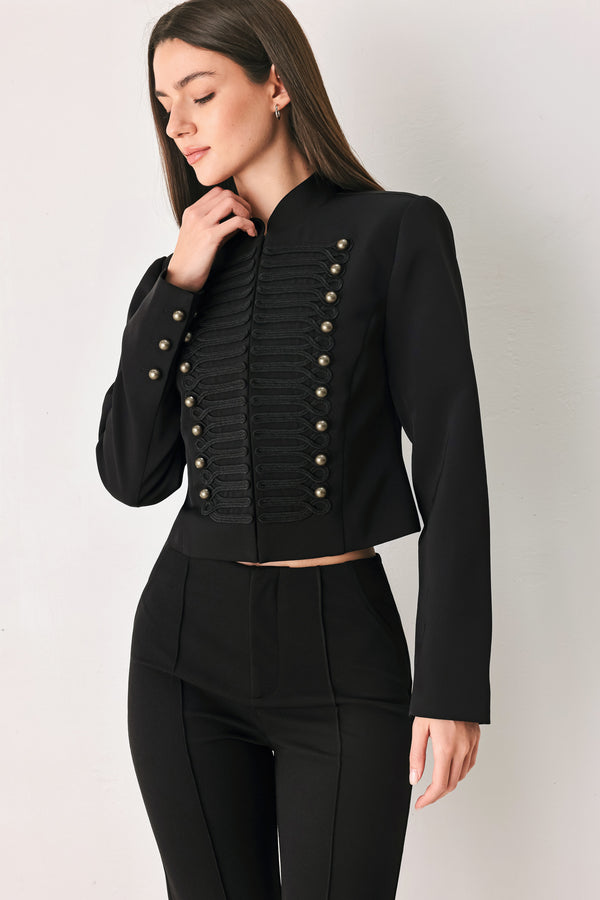 Woman wearing a long-sleeve mock neck black cropped jacket top with double breasted buttons and military style braiding | FREEMARKET