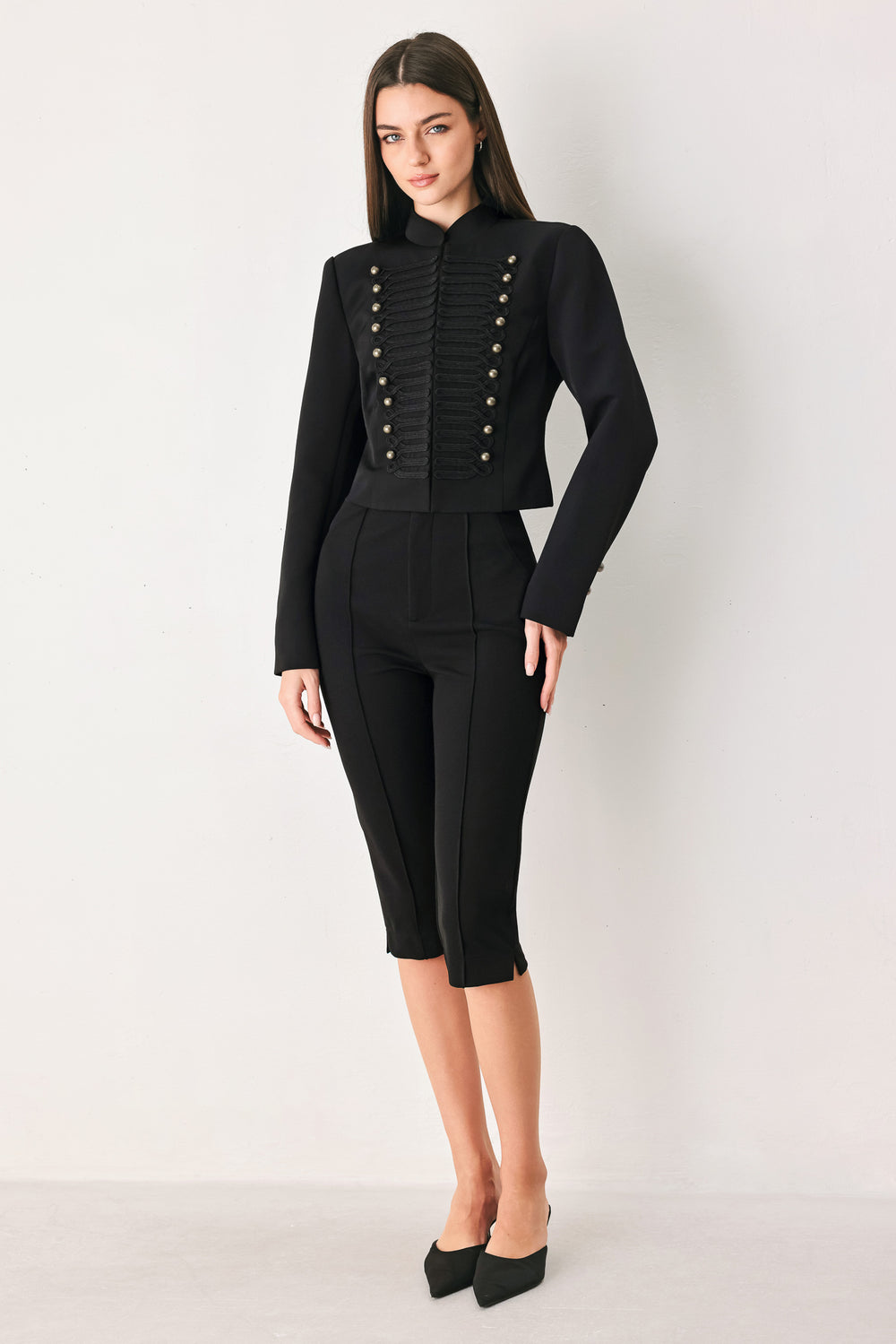 Woman wearing a long-sleeve mock neck black cropped jacket top with double breasted buttons and military style braiding | FREEMARKET