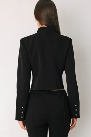 Woman wearing a long-sleeve mock neck black cropped jacket top with double breasted buttons and military style braiding | FREEMARKET