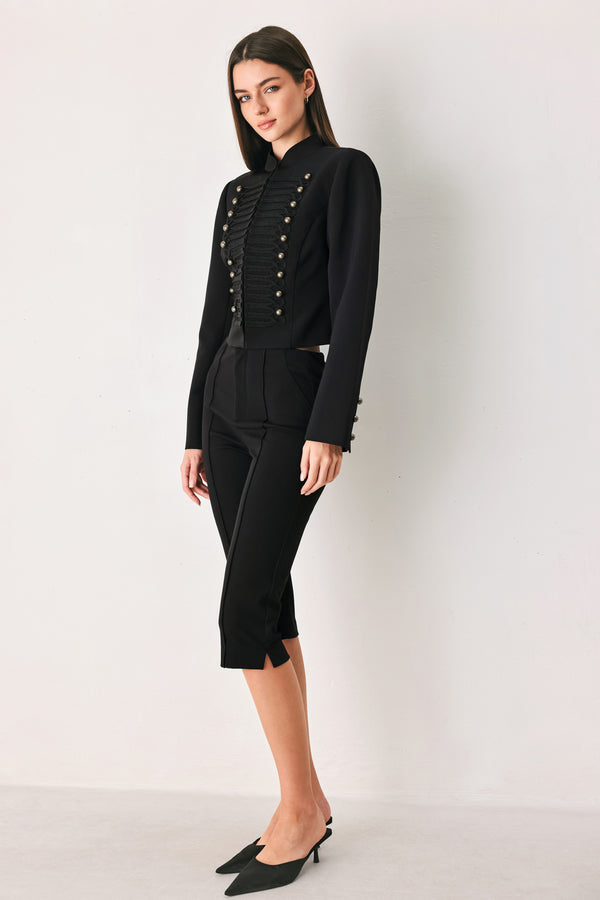 Woman wearing a long-sleeve mock neck black cropped jacket top with double breasted buttons and military style braiding | FREEMARKET