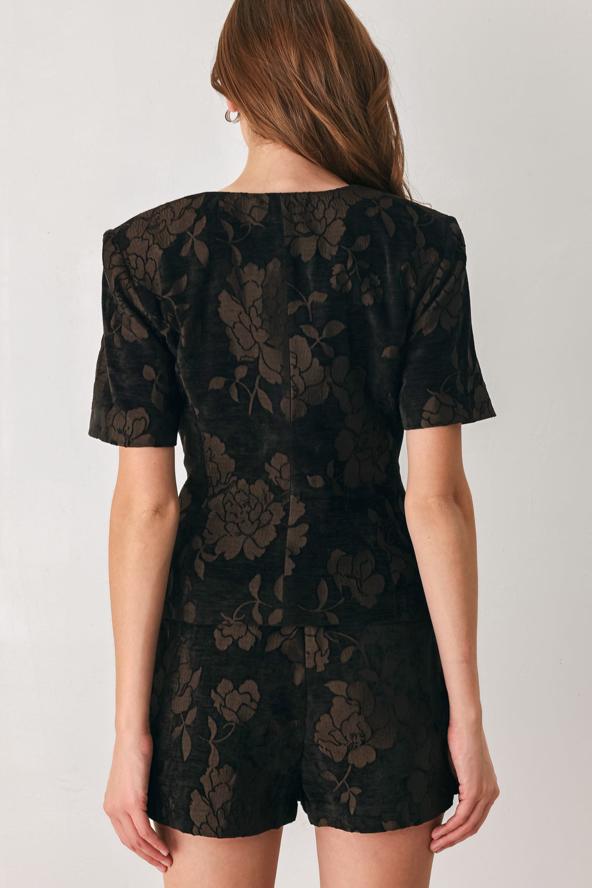 Woman wearing a short sleeve v-neck black top with brown jacquard floral pattern | FREEMARKET