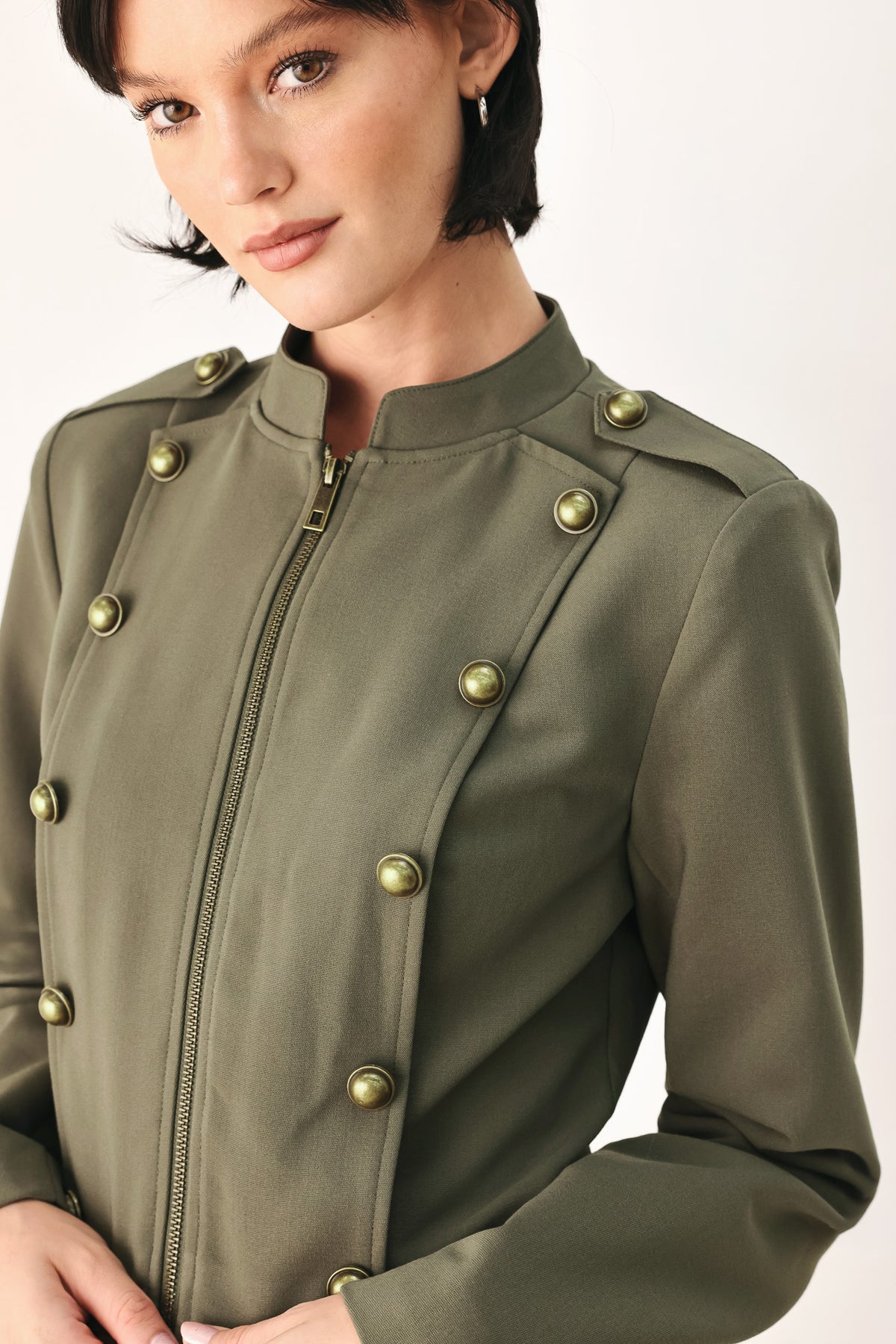 A model wearing an olive green military-style cropped jacket top with gold-tone double-breasted buttons, a front zipper, and a high mock neck | FREEMARKET