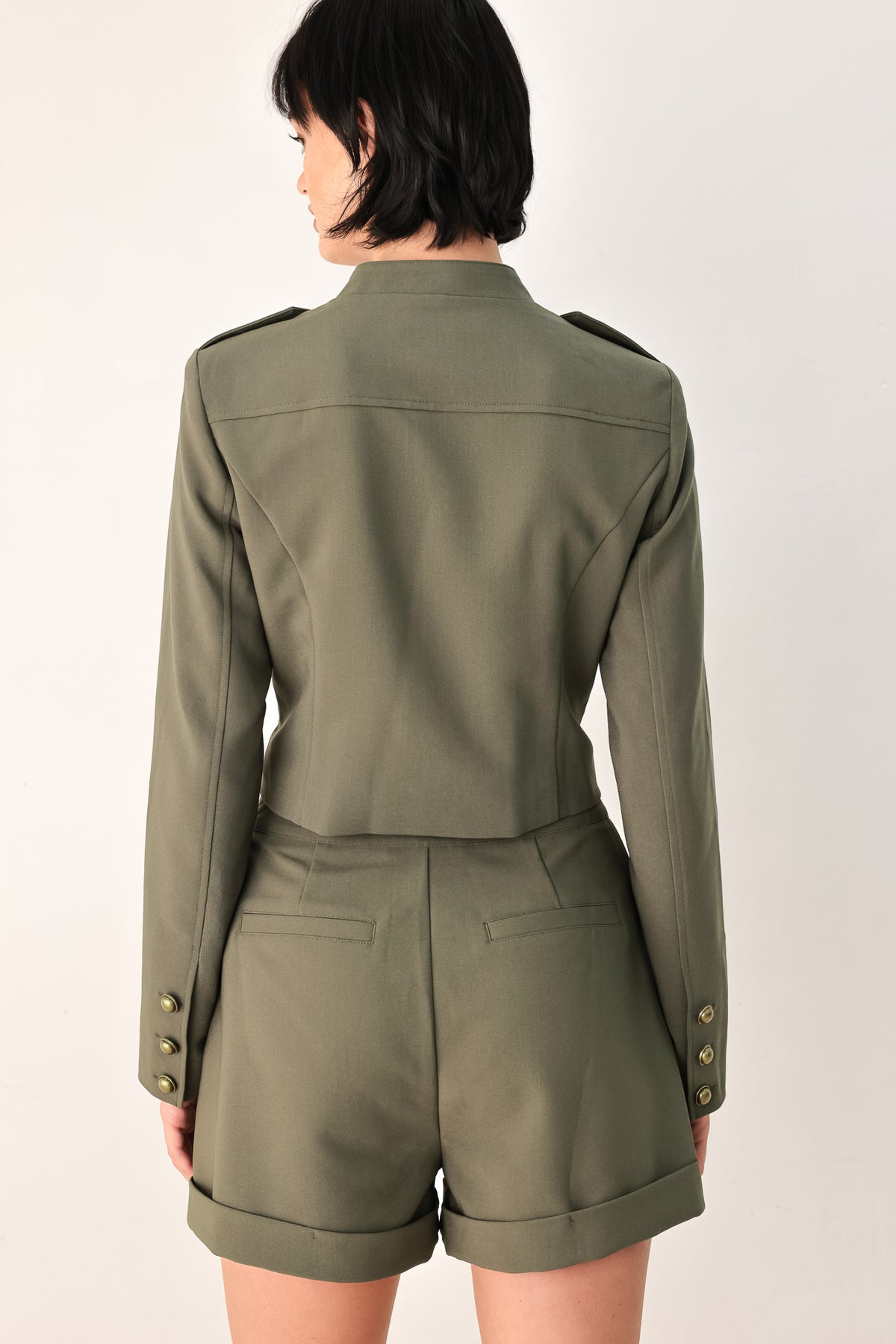 A model wearing an olive green military-style cropped jacket top with gold-tone double-breasted buttons, a front zipper, and a high mock neck | FREEMARKET