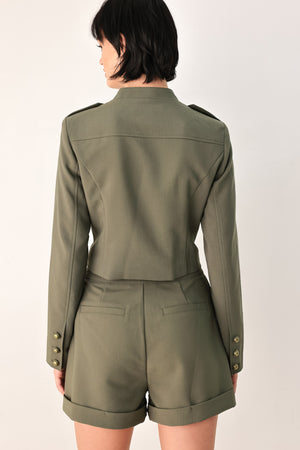 A model wearing an olive green military-style cropped jacket top with gold-tone double-breasted buttons, a front zipper, and a high mock neck | FREEMARKET